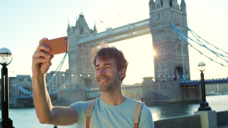 a happy young man smiling and taking a selfie