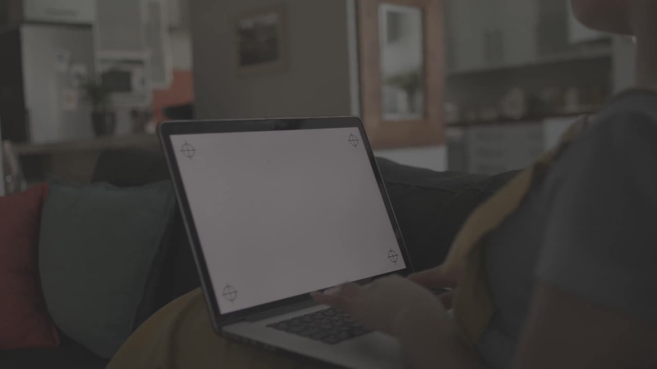 mujer biracial usando una computadora portátil con espacio de copia y sentada en el sofá en cámara lenta