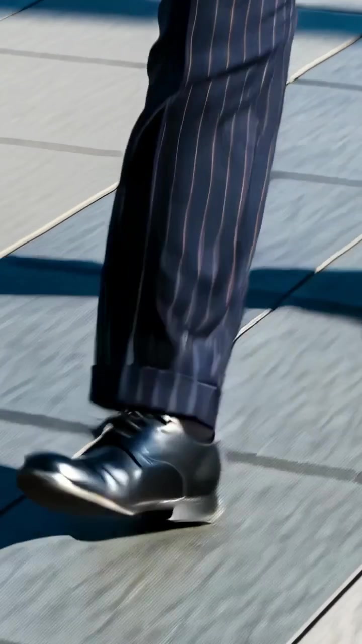 Vertical video: Striding male lower legs crossing tiled plaza, showing pinstripe trousers and shoes