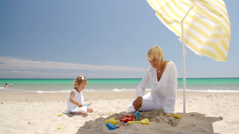 Kleines-Mädchen-Spielt-Mit-Ihrer-Oma-Am-Strand