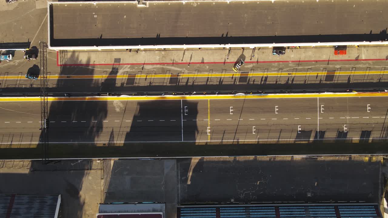 снимок с воздуха сверху вниз тренировочной гонки на гоночной трассе и машин, готовящихся на пит-лейн