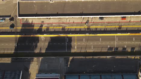 aerial top down shot of training race on racetrack and cars preparing in pit lane