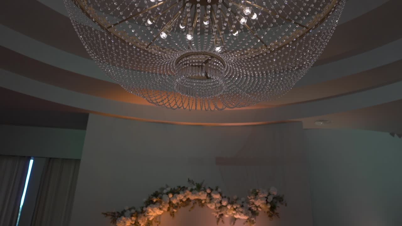 illuminated chandelier with intricate details, paired with soft floral decorations in the background