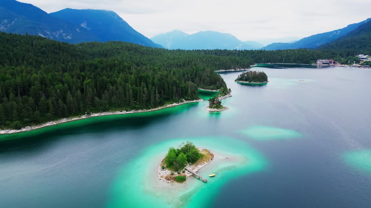 아름다운 빛나는 호수의 다채로운 공중 풍경, 넓은 소나무 들판에 둘러싸여, 배경에는 웅장한 산들이 있습니다.