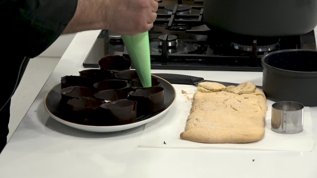 In a contemporary kitchen, a chef skillfully prepares chocolate cups while baking fresh cookies. Watch as delicious desserts come to life with fun decorating tips.
