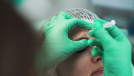 cosmetologist does anti-aging injection into client forehead