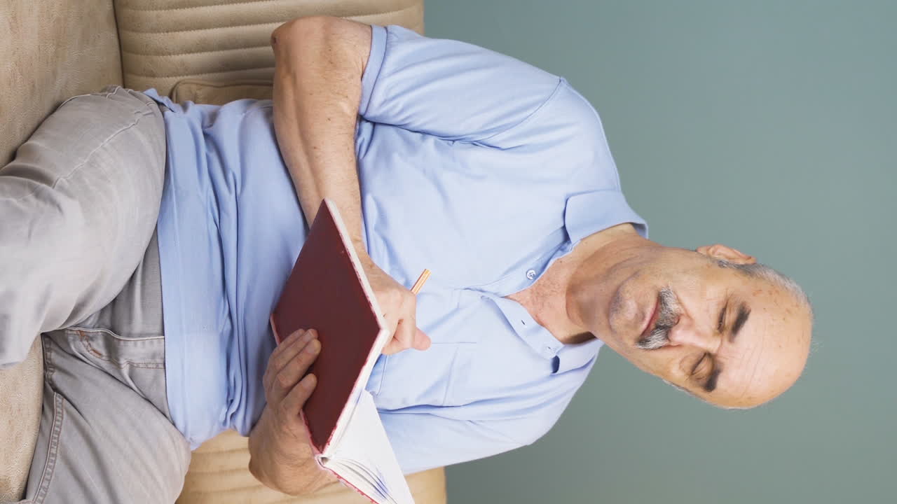 vídeo vertical de un anciano tomando notas en un cuaderno.