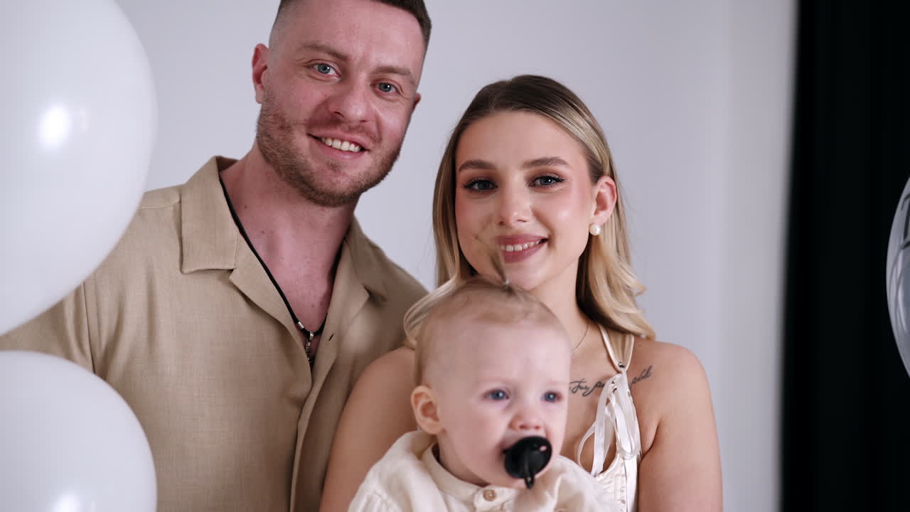 Beautiful Caucasian parents with their adorable little baby. Happy couple kissing and kiss their beloved child.