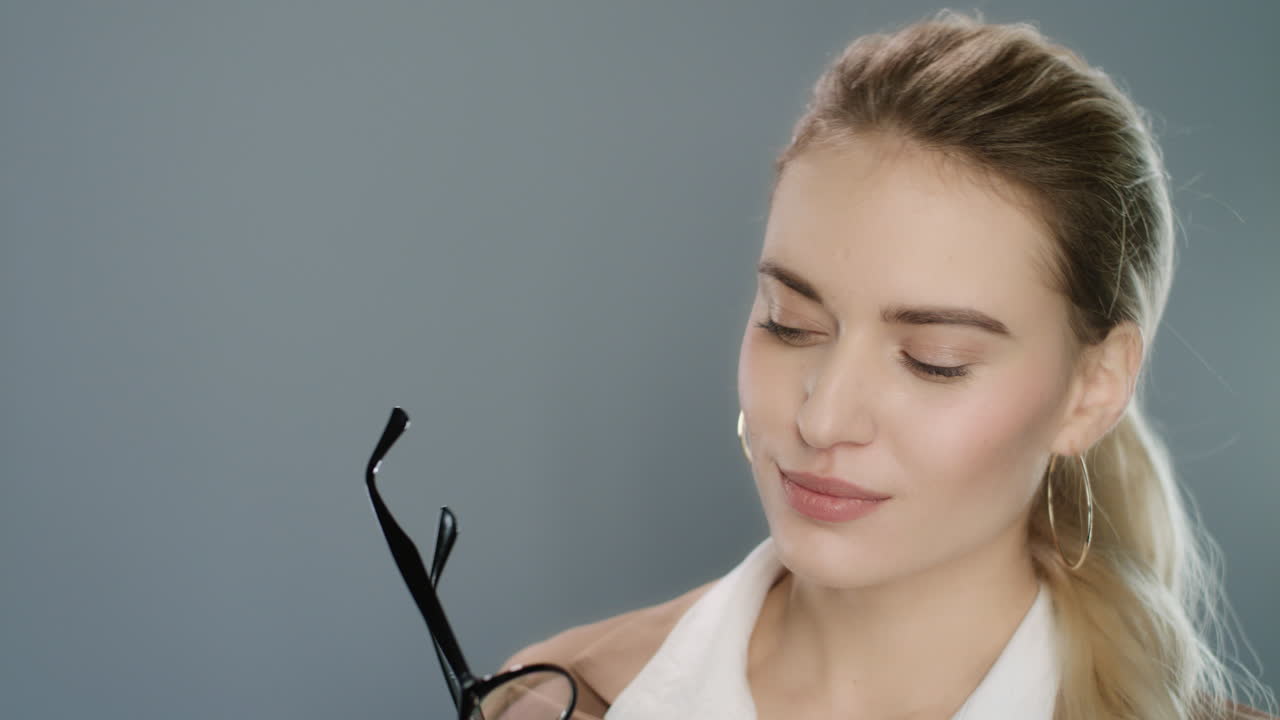 mujer seductora con cola de cabello con gafas en la mano y ojos parpadeantes