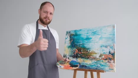 an artist in a work coat records a video blog as he paints a picture with brushes on a white canvas - an artist in a work coat records a video blog as he paints a picture with brushes on a white canvas. the process of creating an oil painting in the workshop