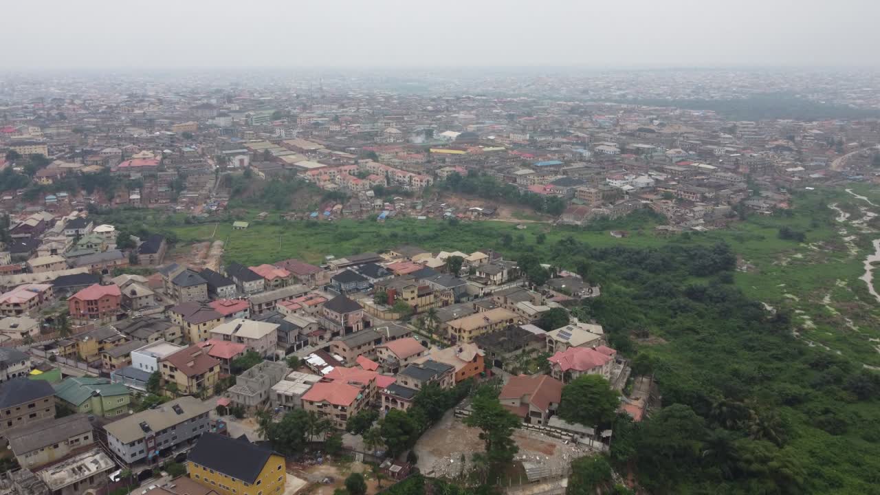 Luftfoto af et kvarter i Lagos, Nigeria, på en diset dag med grøn vegetation ved siden af kvarteret