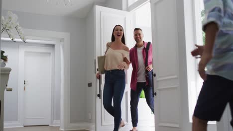 excited caucasian son and daughter at home running to greet parents coming through the front door