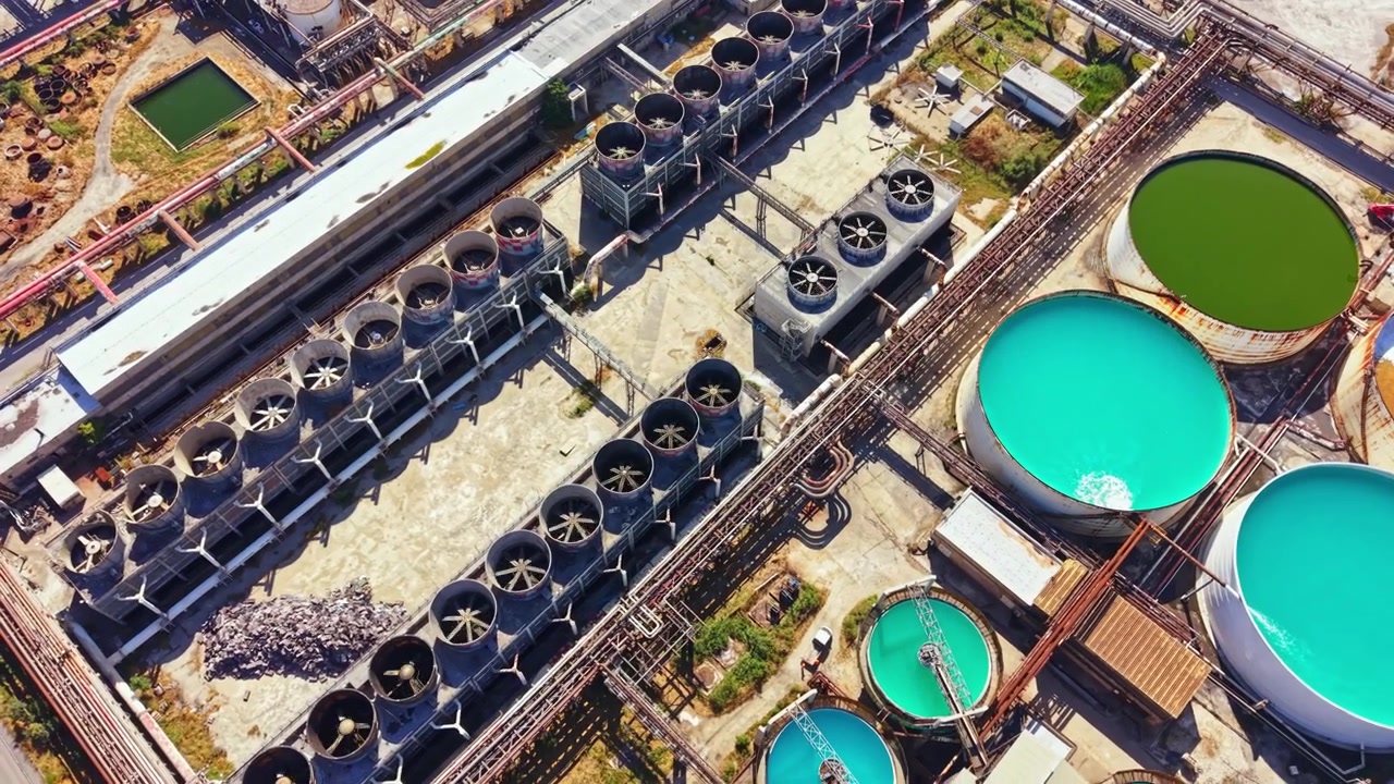 View of industrial water treatment facility with large tanks and cooling towers during daylight