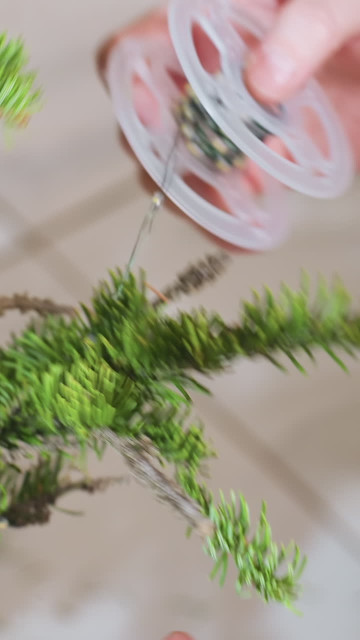 Creating festive holiday decoration, Artisan hands assemble Christmas greenery with lights, Detailed shot of skilled artisan arranging fir branches and LED lights into festive decoration