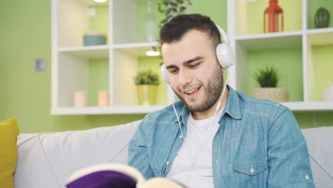 un estudiante universitario feliz leyendo un libro en casa escuchando música.