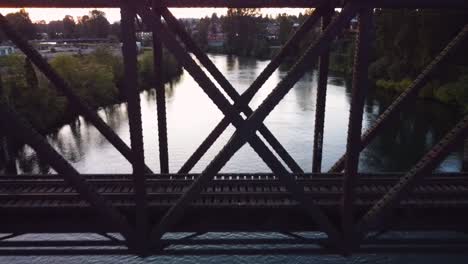 Drone-Flying-Backwards-Through-Railroad-Bridge-above-Snohomish-River-in-Snohomish,-WA