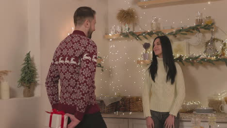 Man-Giving-A-Surprise-Christmas-Gift-For-Woman-At-Home