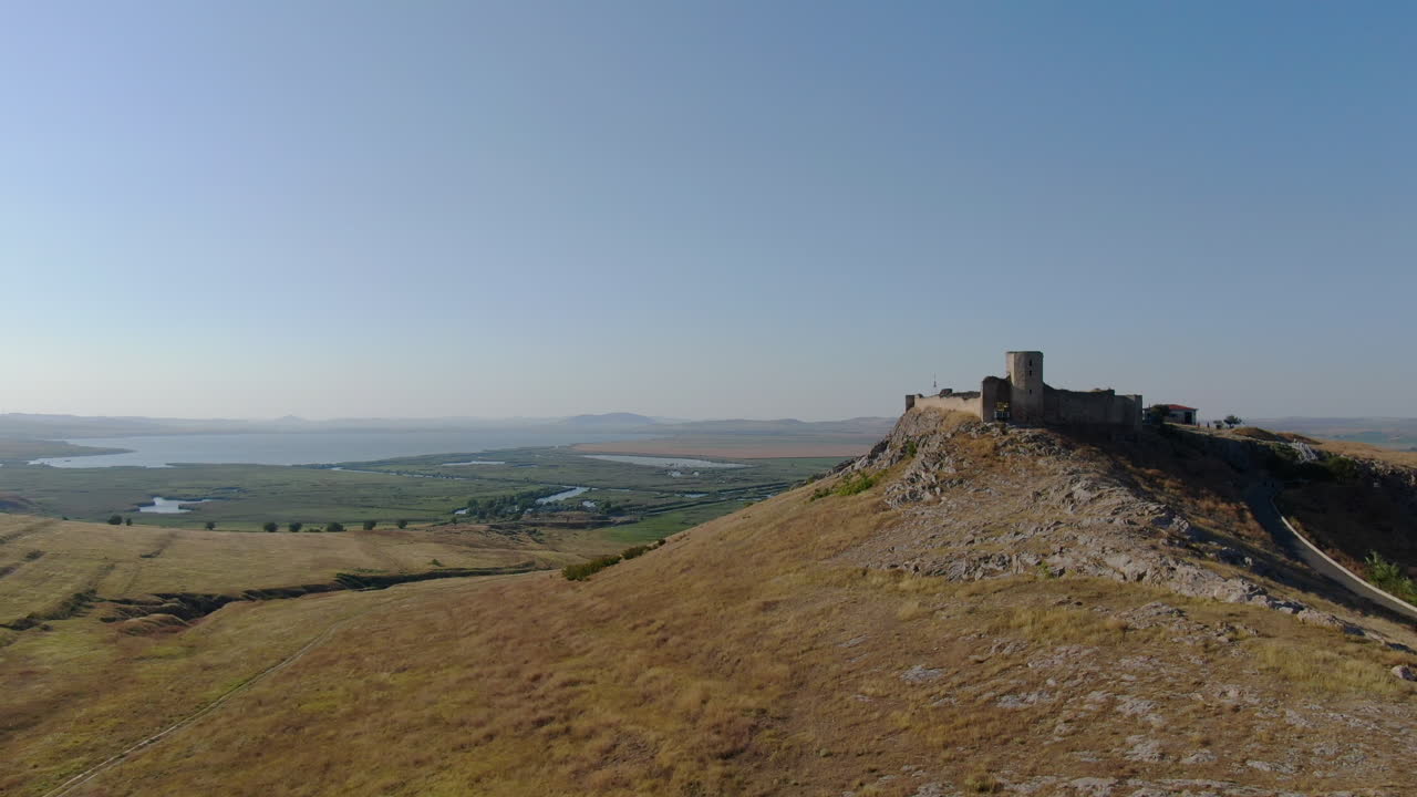 toma aérea de drones con la parte frontal de enisala, fortaleza medieval en la cima de una colina rodeada de lagos y llanuras en un día claro y soleado
