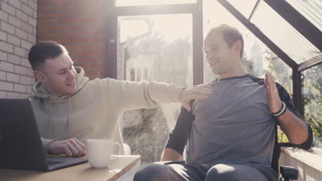 happy disabled man in wheelchair giving high five to his friend at home