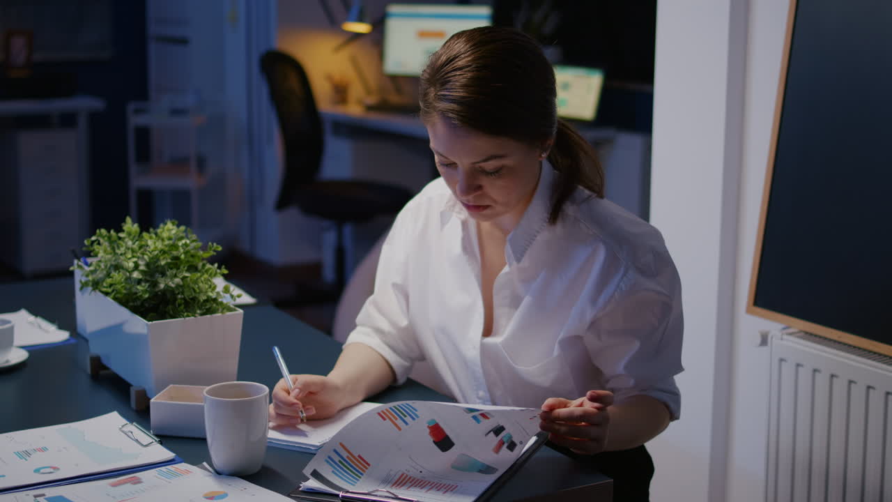 Overworked businesswoman writing financial profit on notebook while working in business company meeting