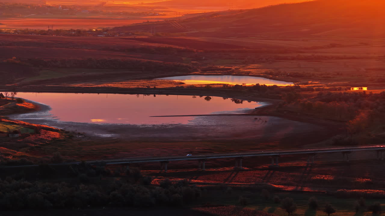 Aerial drone view of a tranquil lake reflecting the warm golden light of sunset in rural Moldova