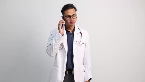 Asian doctor man talking on phone, celebrating a success. Smiling, happy and cheering after a good news. Isolated on white background