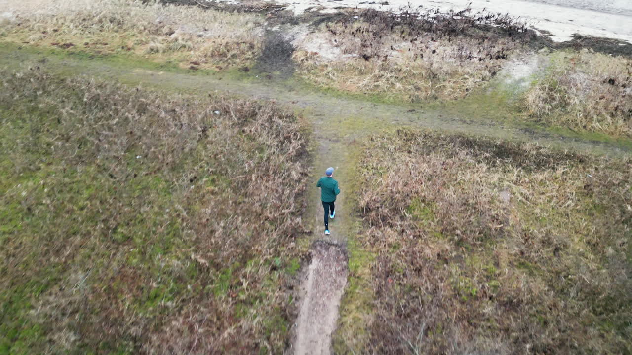 Aerial view of runner on a rural path in early morning near the beach