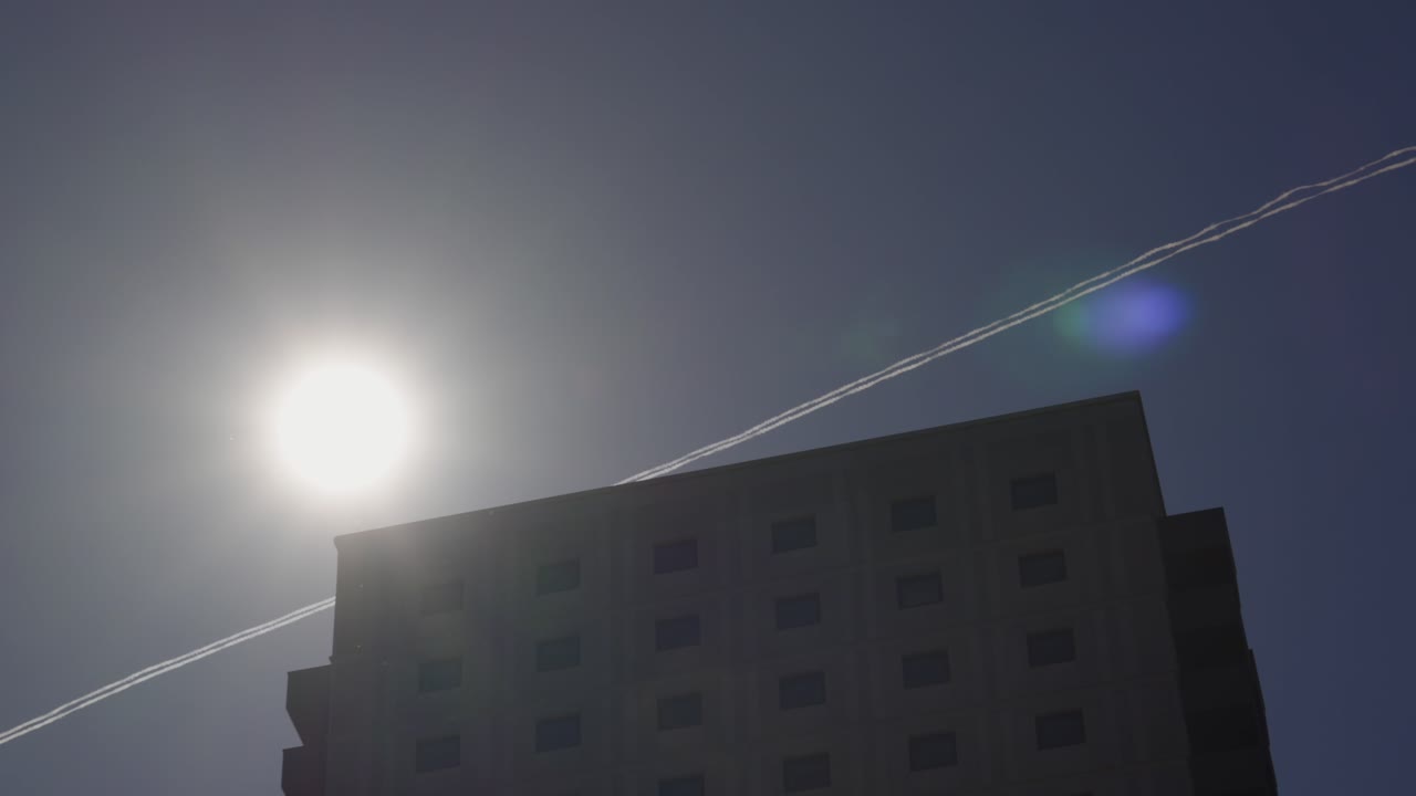 Destello solar detrás de un complejo residencial contemporáneo de gran altura en Londres, Reino Unido. Ideal para marketing inmobiliario, estilo de vida urbano o contenido sobre la vida en la ciudad. Estela de avión en el fondo