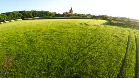 A-beautiful-aerial-over-yellow-fields-with-a-church-distant-in-England