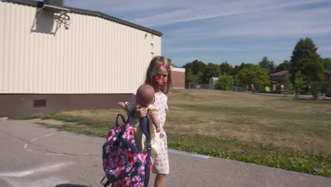 a little girl walking through a school yard wearing a face mask