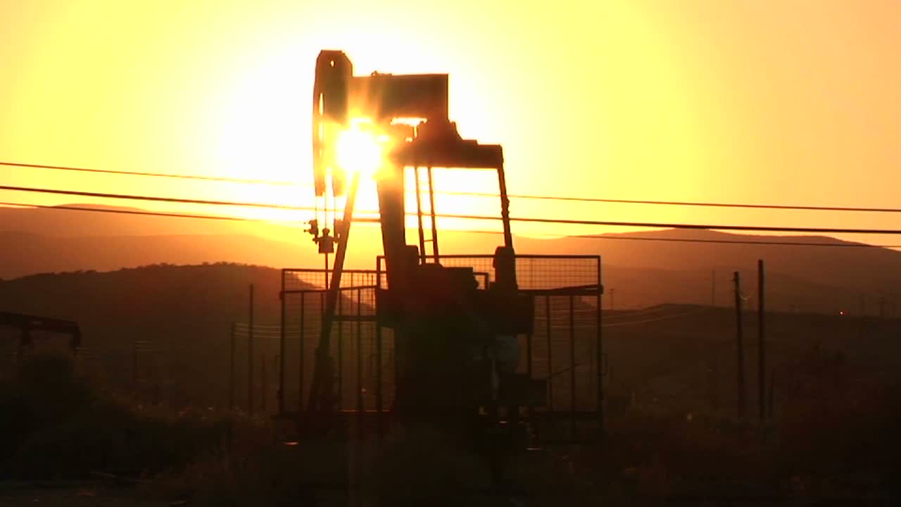 una torre de perforación de petróleo bombea al atardecer
