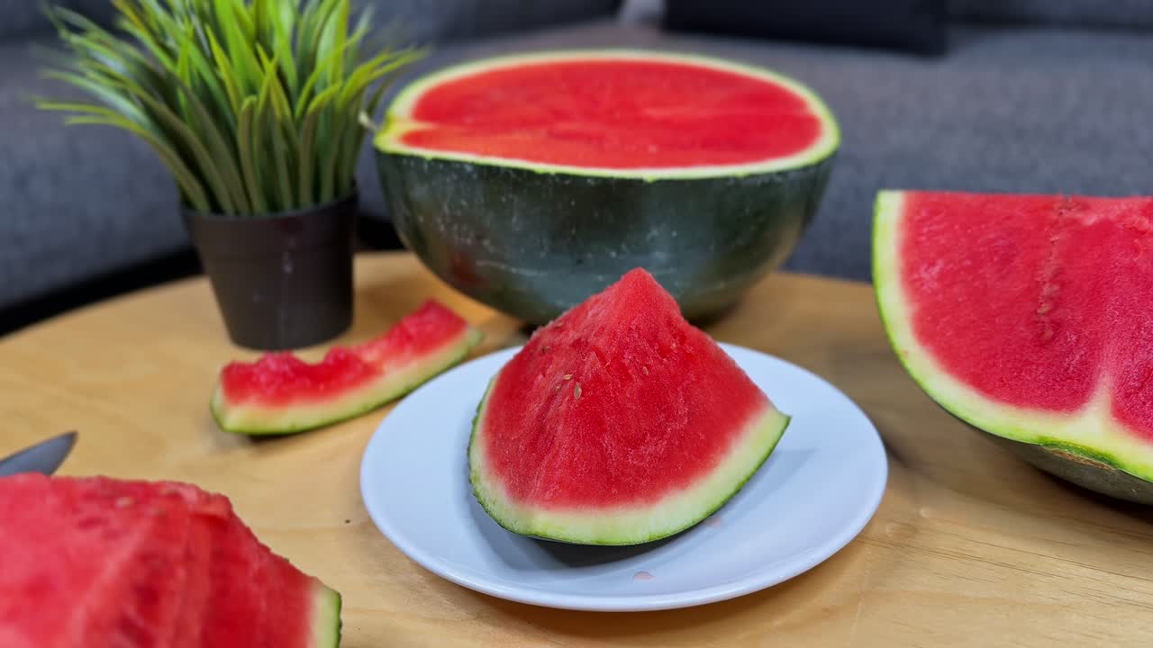 Close-up of fresh juicy watermelon slice on a plate with more fruit in the background, ideal for food, health, summer, and nutrition projects
