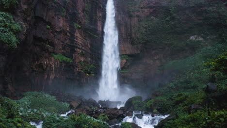 aerial tilt shot backwards from the air terjun kapas biru falls, in java, indonesia