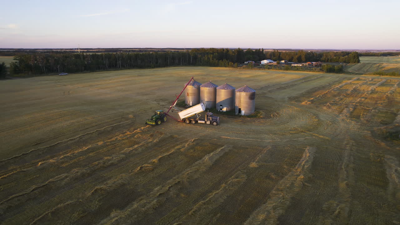 Große Silos und Traktoren entladen Erntegüter in Red Deer County, Alberta, Kanada – Drohnenaufnahme