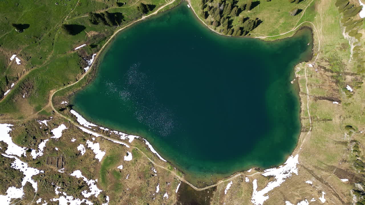 Bird's eye view drone shot of Lake Lioson during the day with snow in Ormont-Dessous, near Les Mosses, in the canton of Vaud, Switzerland