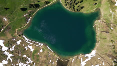 bird's eye view drone shot of lake lioson during the day with snow in ormont-dessous, near les mosses, in the canton of vaud, switzerland
