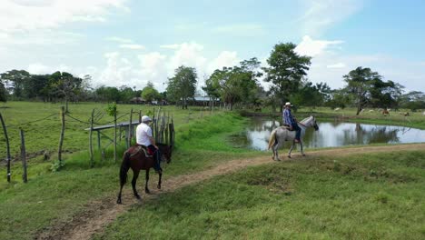 aerial shot of men riding horses in a beautiful farm