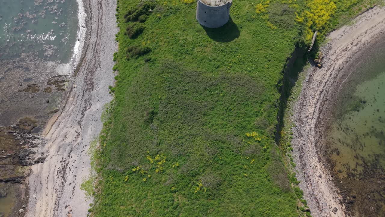 Aerial Revealing Shot Of Coastal Martello Tower Surrounded By Green Grass On Shenick Island In Ireland