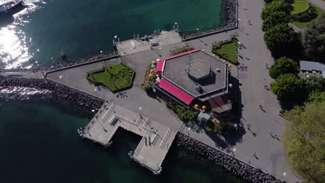 Upward-aerial-tilt-above-a-restaurant-and-dock-along-Lake-Geneva-in-Lausanne,-Switzerland-on-a-sunny-day