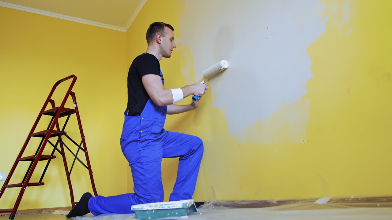 Professional repairman renovating the room. Handsome painting master doing room renovation.