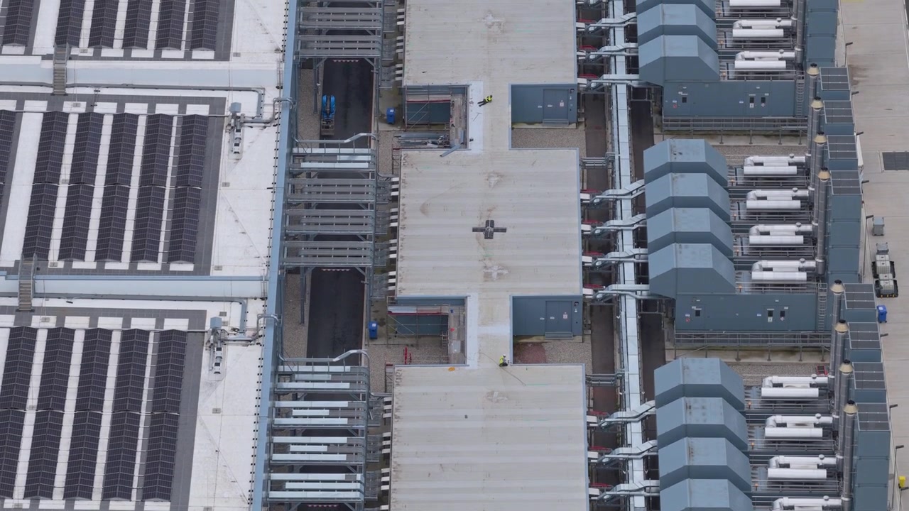 Fugleperspektiv af et stort, moderne hyperscale datacenter, der afslører dets komplekse kølesystemer på taget og avancerede infrastruktur