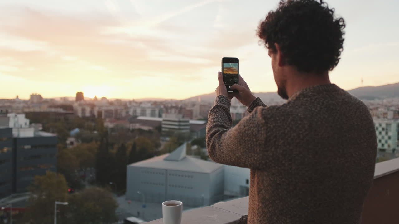 Man taking picture of cityscape at sunset