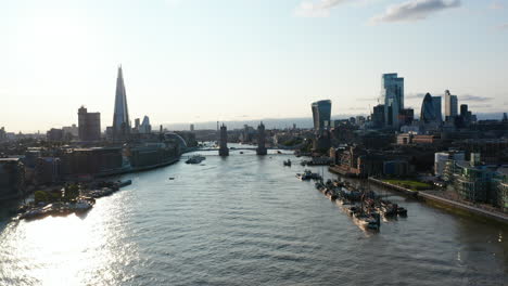 Ascending-panoramic-footage-of-River-Thames-and-skyscrapers-on-both-banks.-Water-surface-reflecting-sunshine.-London,-UK