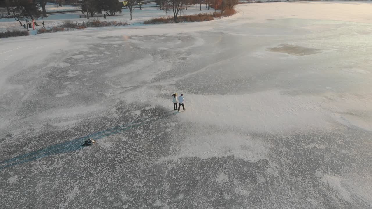 pareja caminando sobre un lago congelado durante la puesta de sol