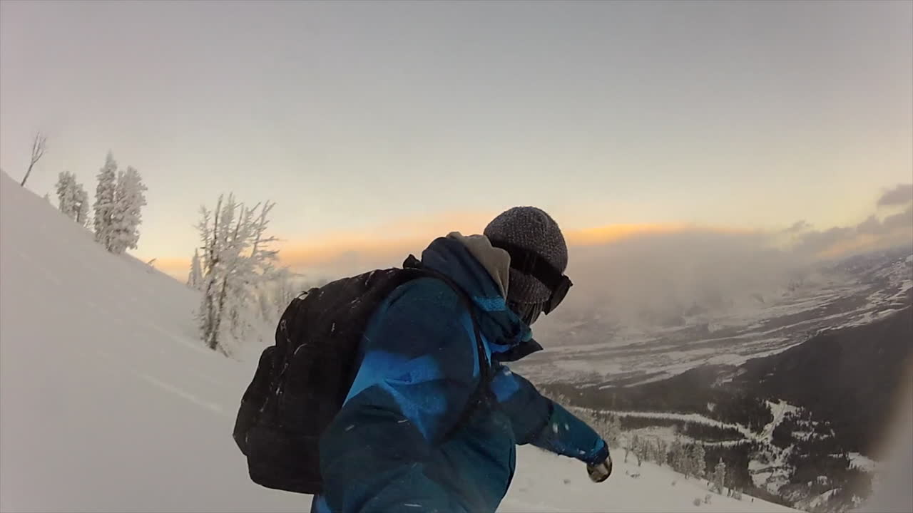 snowboarder masculino gopro seguir selfie backcountry polvo cámara lenta cinematográfica mitad del invierno nieve fresca puesta de sol teton paso jackson agujero enero congelamiento frío