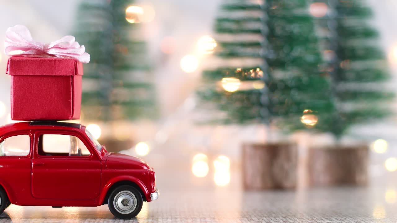 Macchinina rossa con un regalo di Natale rosso sul tetto e luci lampeggianti.