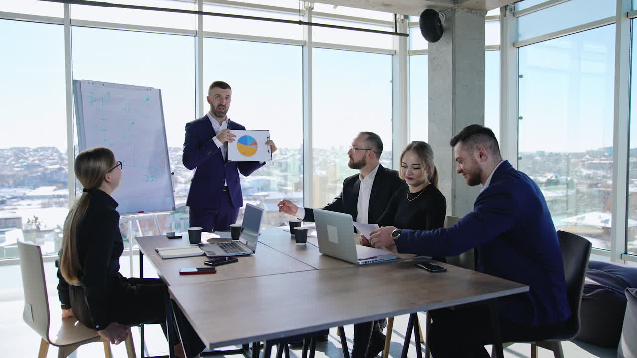 Communication and discussion at the business meeting. Cooperative team discussing charts at the table in the office. Cityscape at the backdrop.