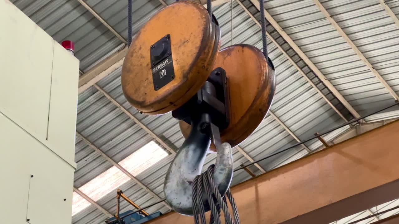 Crane pulley, hook and steel wire rope mechanism in an indoor industrial facility. Mechanical movement and rugged engineering equipment, ideal for heavy machinery or factory operations content