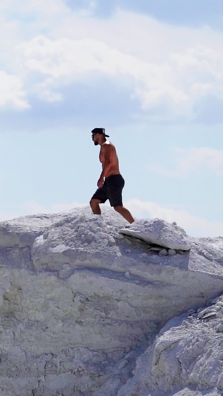Man on a top of a mountain. Young man standing on cliffs edge of top of the mountain Vertical video