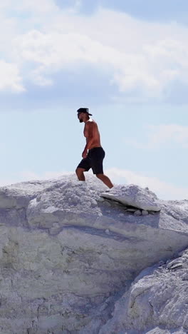 man on a top of a mountain. young man standing on cliffs edge of top of the mountain vertical video